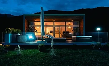 Illuminated Eden Hill villa and terrace hot tub seen from the garden at night.