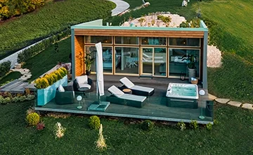 Glass-fronted Eden Hill villa with loungers and a hot tub on its wooden terrace.