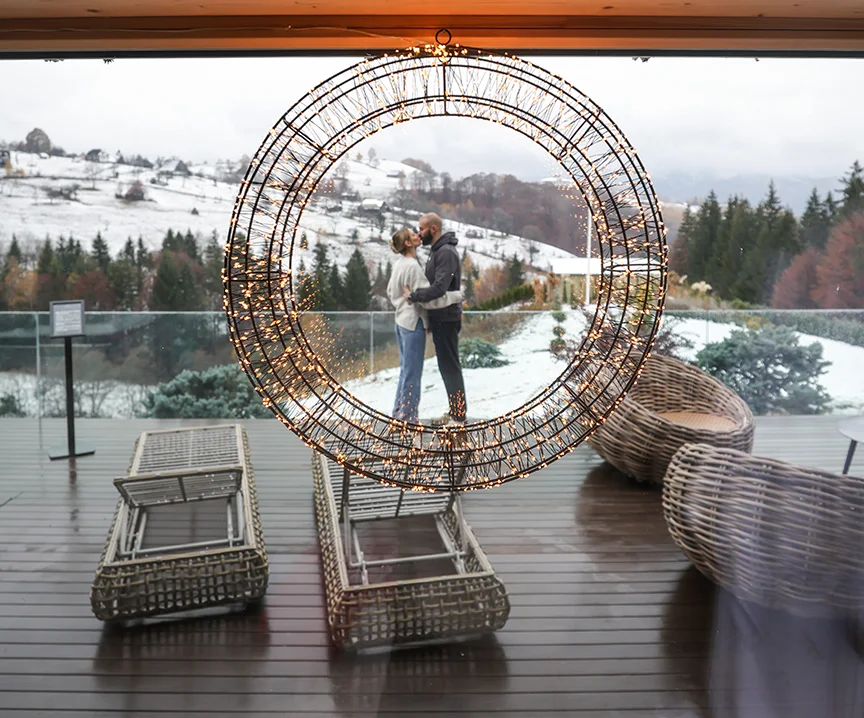 Snow-covered Eden Hill terrace with loungers and a couple beneath a circular arch.