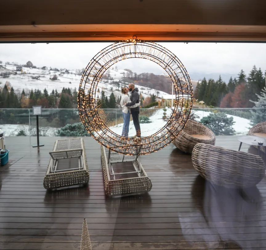 Couple beneath a decorated arch on a snowy Eden Hill terrace, with loungers in the foreground.