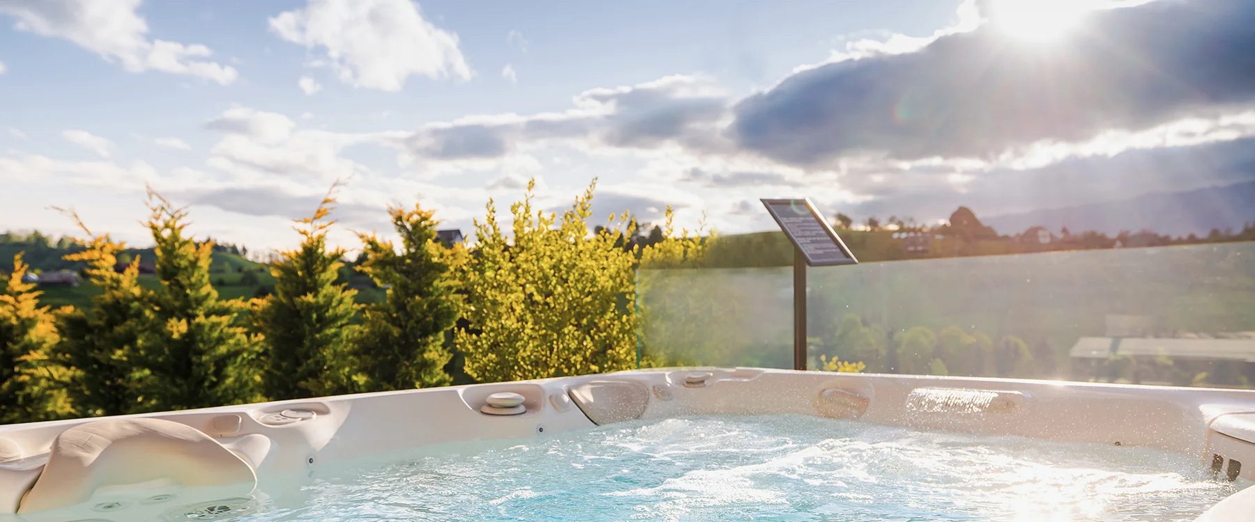 Jacuzzi cu apă învolburată pe terasa Eden Hill, lângă balustrada de sticlă, în lumina apusului.